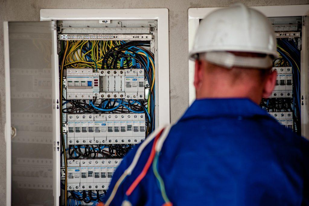 Electrician in blue coveralls and white helmet - Visit Phaselectric.com.