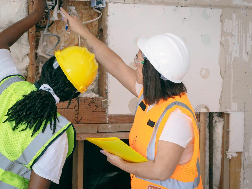 Female electricians in hard hats examining wiring - Visit Phaselectric.com.