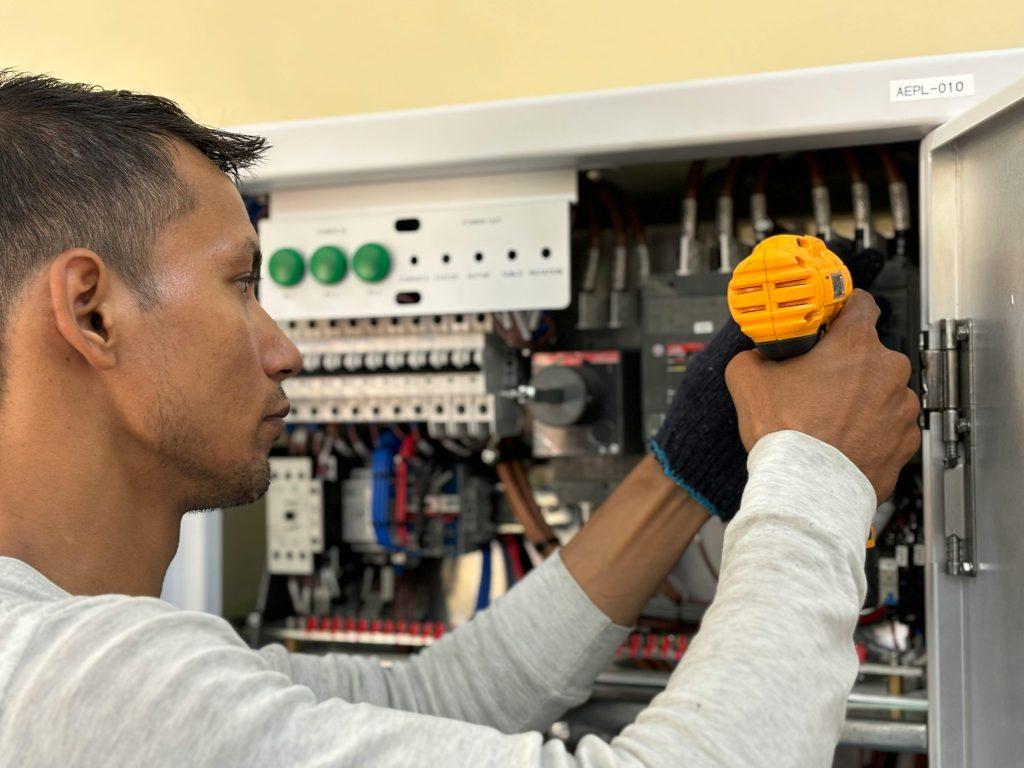 Electrician using electrical screwdriver in breaker panel - Visit phaselectric.com.