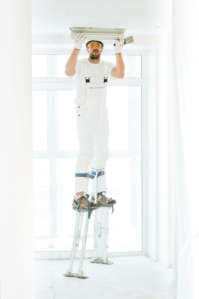 A professional contractor on stilts lifting a panel into a wall - Contact Phaselectric.com. 